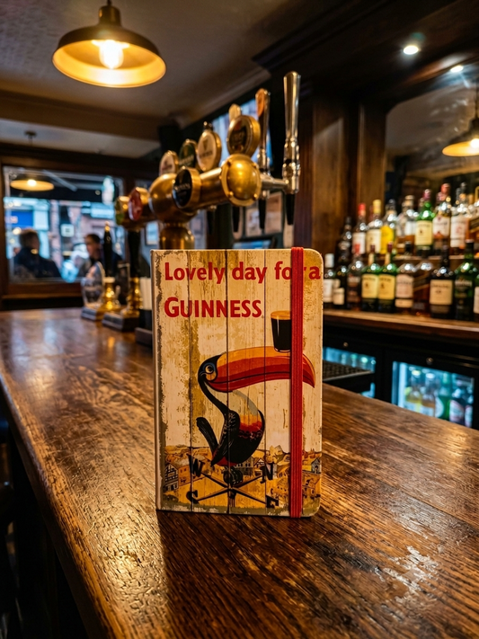Wooden sign with a toucan illustration and 'Lovely day for a GUINNESS' text on a bar counter.